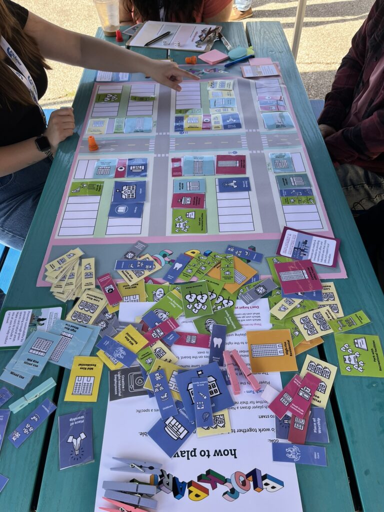 Two people playing (faces not shown) playing a board game activity at the Block Party engagement event.